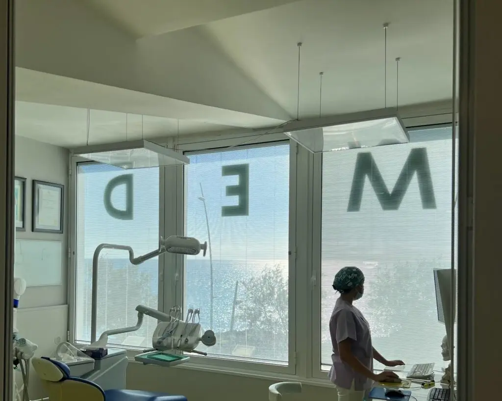 Studio dentistico con vista mare e operatore sanitario.