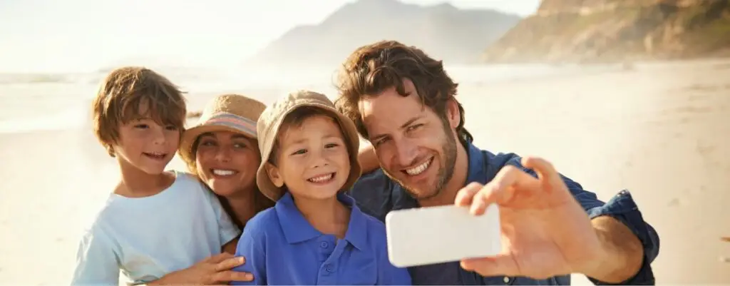 Famiglia felice scatta selfie sulla spiaggia.