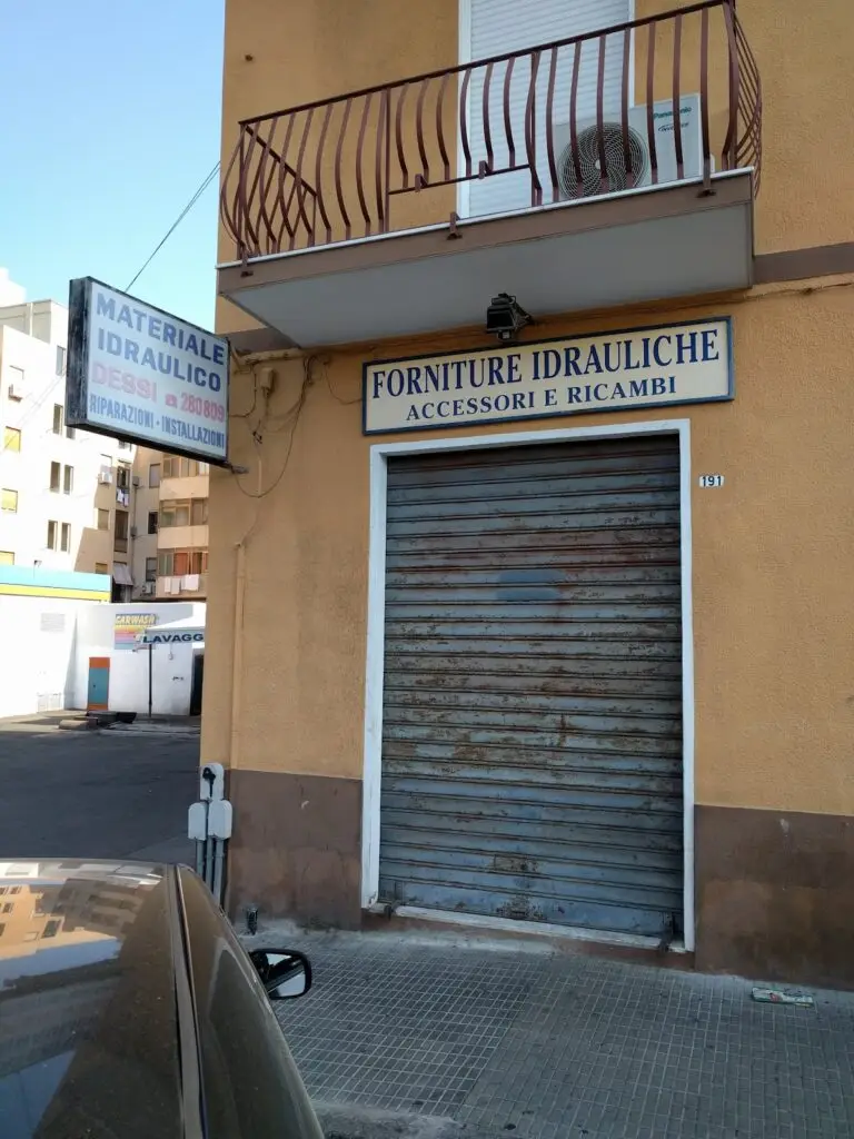 Negozio idraulica chiuso, insegne e strada deserta.