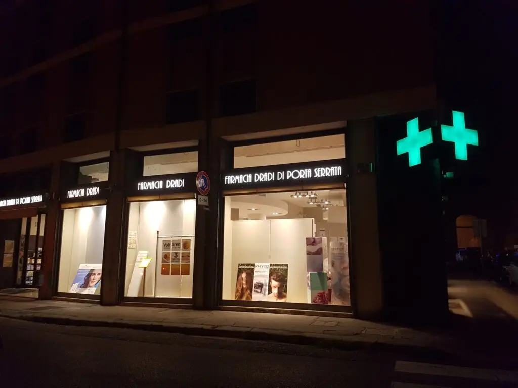 Farmacia notturna illuminata con croce verde.