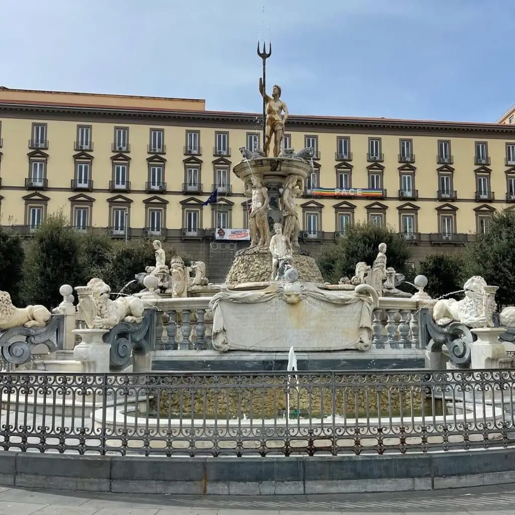 Fontana storica con statue e palazzo sullo sfondo.