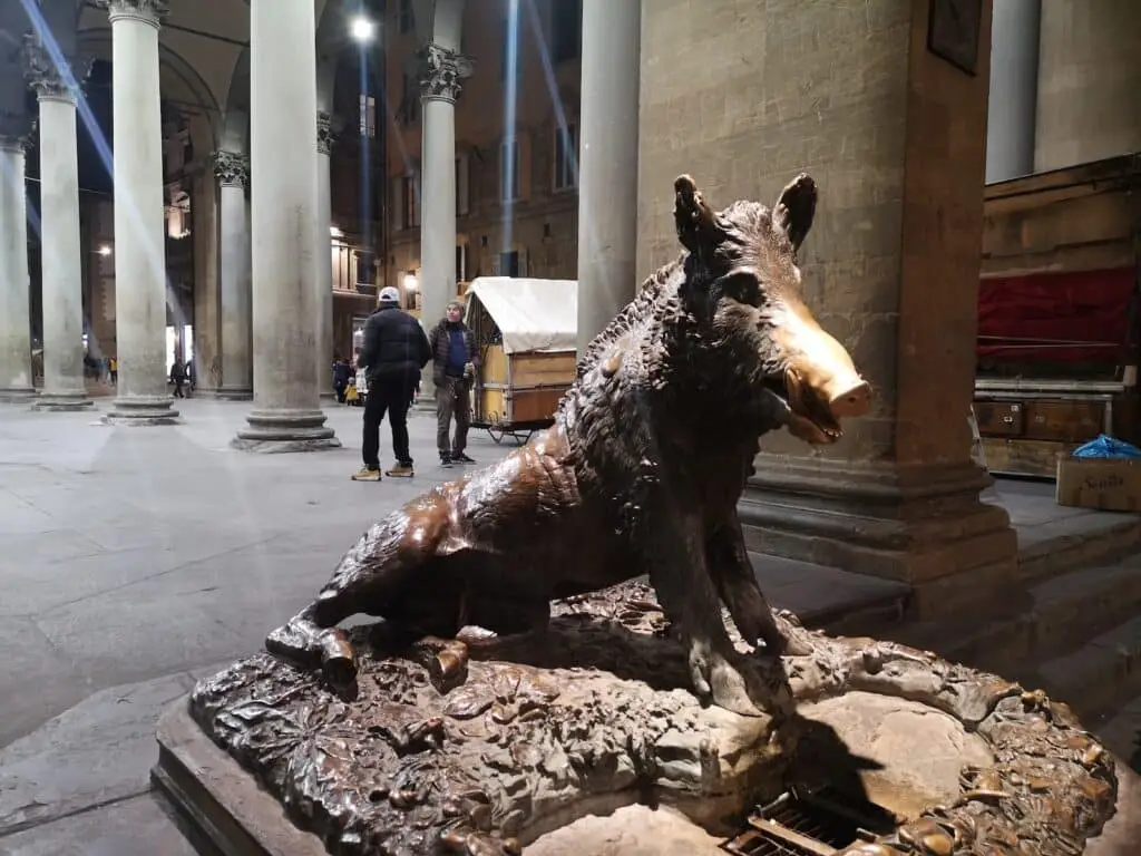 Statua del cinghiale in bronzo illuminata.