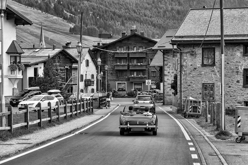 Villaggio alpino con auto d'epoca in strada.