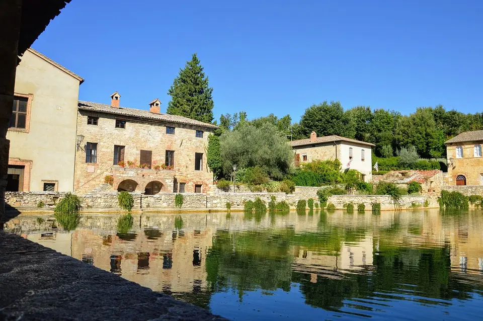 Case rurali riflettenti su lago calmo in Italia.