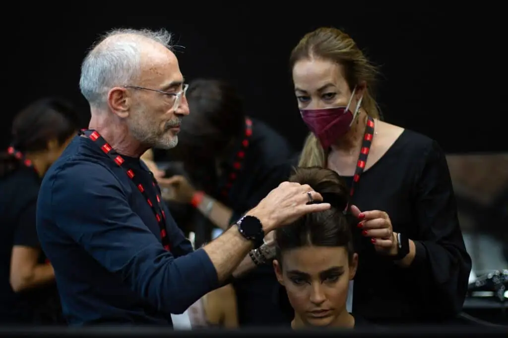 Parrucchiere stilizza capelli di una modella.