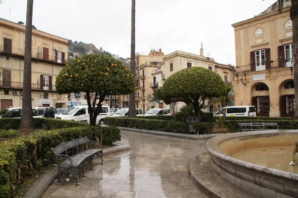 Piazza italiana con alberi di aranci e panchine.