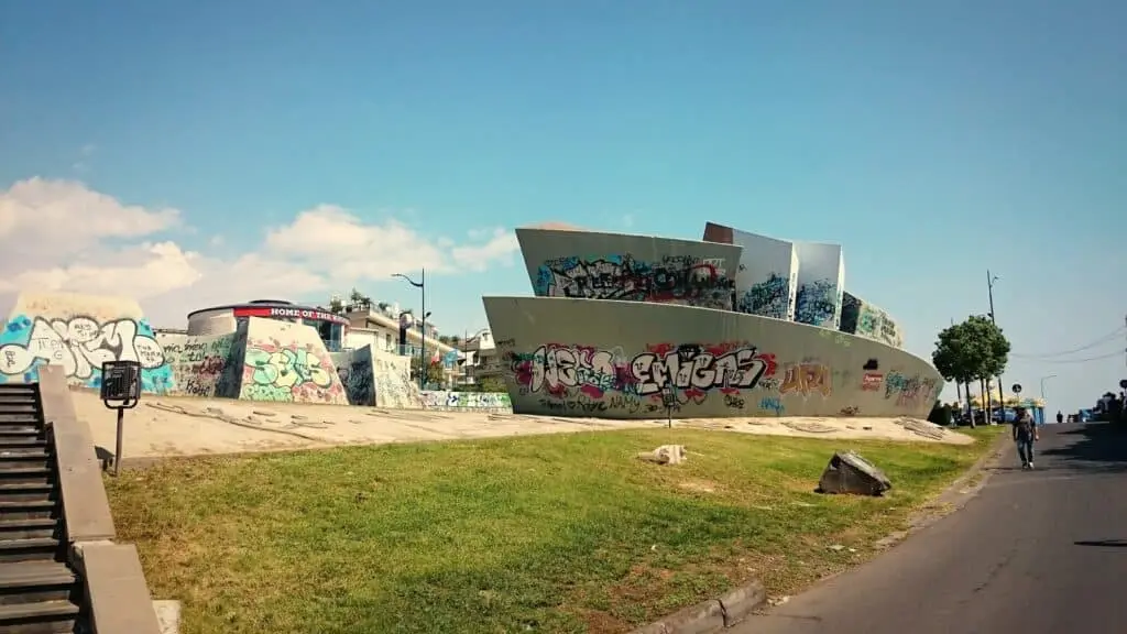 Skatepark urbano con graffiti e cielo azzurro.