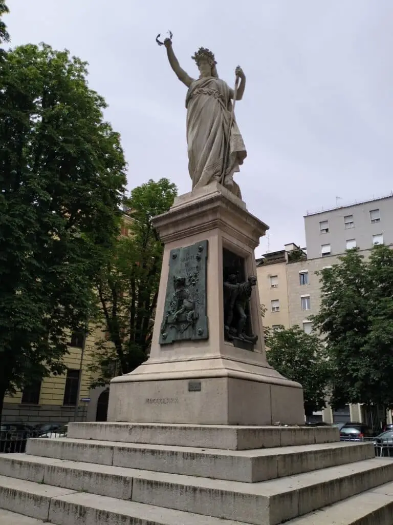 Statua monumentale in piazza con basamento scultoreo.