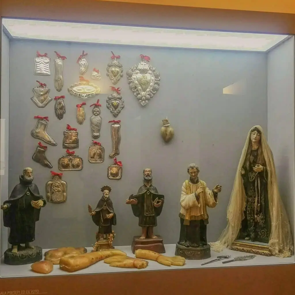 Ex voto e statue religiose in vetrina museale.