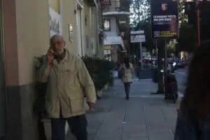 Uomo anziano parla al telefono sulla strada.