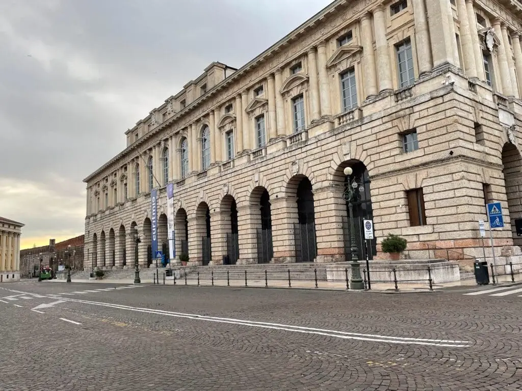 Palazzo storico con arcate e strada acciottolata.