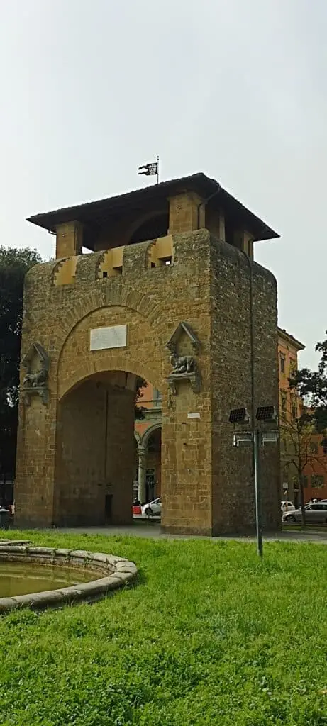 Torre medievale con bandiera e fontana antistante.