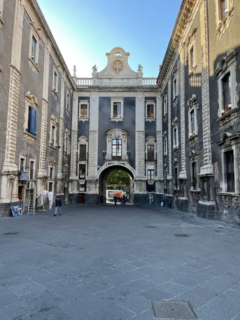 Piazza storica con monumentale arco in pietra.