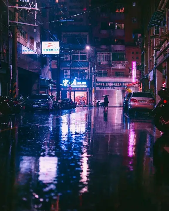 Strada cittadina illuminata e bagnata di sera.