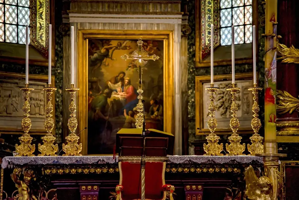 Altare barocco con candele e croce in chiesa.