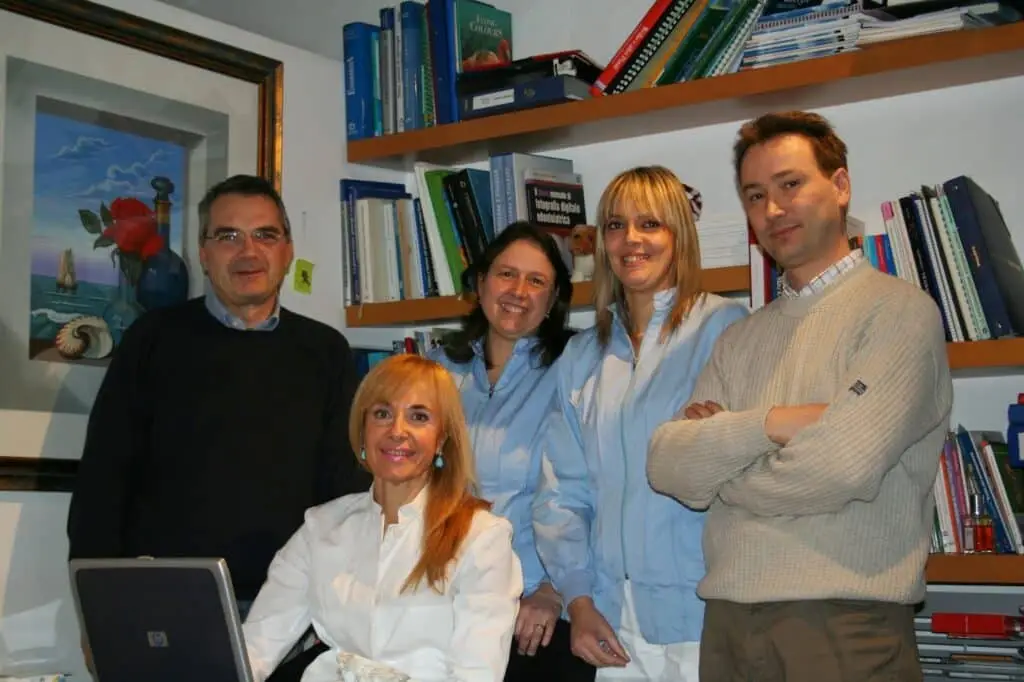 Gruppo di colleghi sorridenti in ufficio con libri.