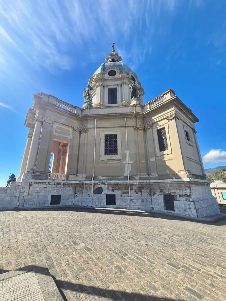 Chiesa barocca sotto cielo azzurro con nuvole sottili.