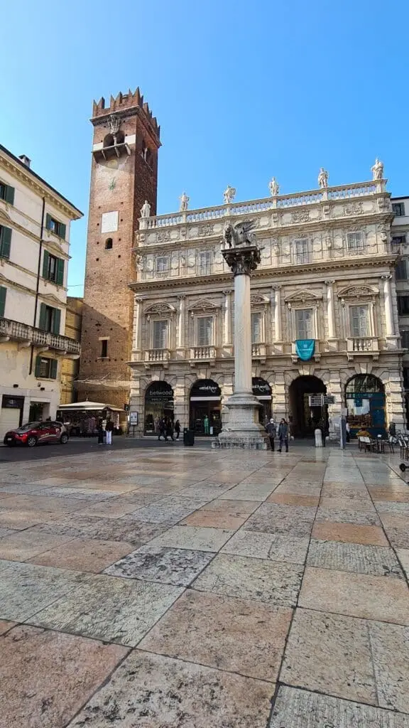 Piazza storica con colonna e torre in Italia.