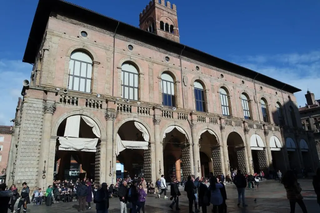 Palazzo storico in piazza con persone e archi.